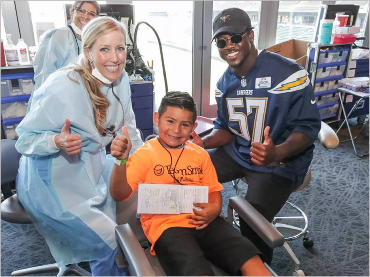 Los Angeles Chargers linebacker Jatavis Brown visits a young patient during TeamSmile’s 2018 outreach program with Biolase.