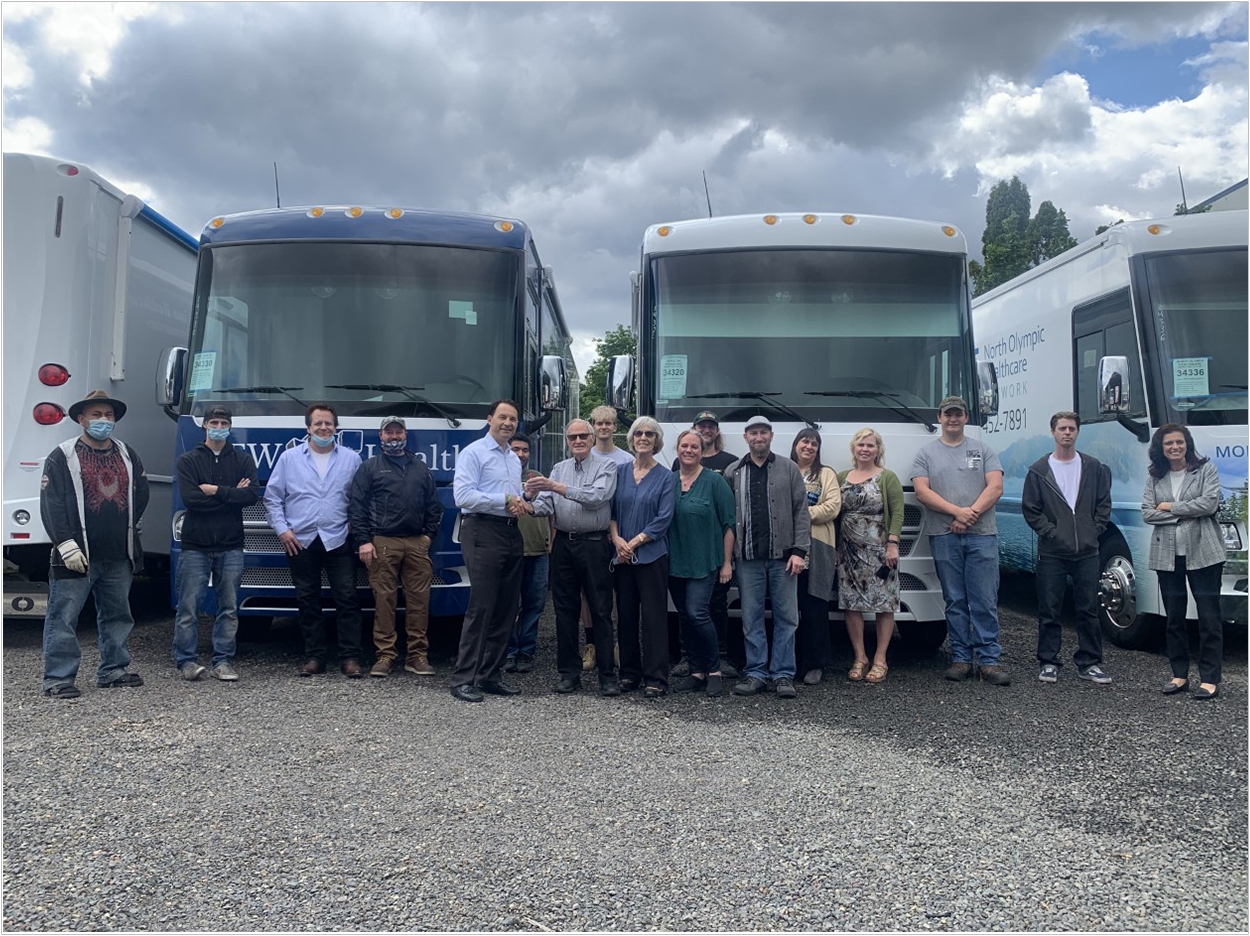 Benco Dental managing director Chuck Cohen (center left) receives the keys to ADI Mobile Health from its founder, Tim Kitch, surrounded by members of the ADI team.